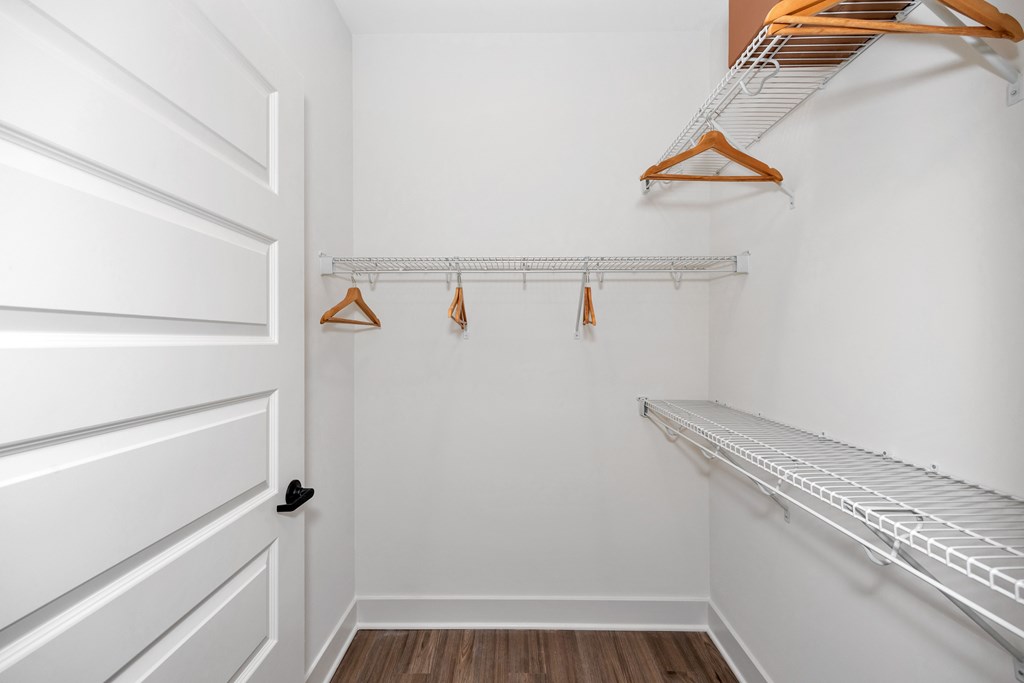 A white closet with a white door and a white shelf.
