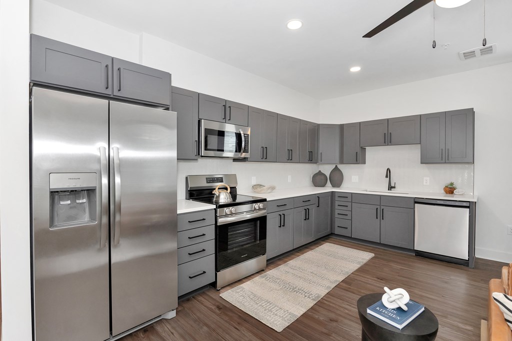 A modern kitchen with a stainless steel refrigerator and wooden flooring.
