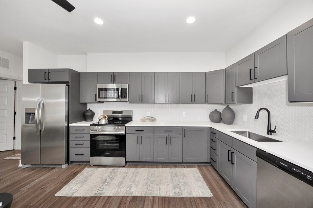 A modern kitchen with stainless steel appliances and wooden flooring.