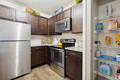 A kitchen with a refrigerator, microwave, oven, and dishwasher.