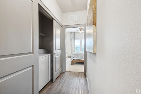 A small, white-walled room with a wooden floor and a small bed in the corner.