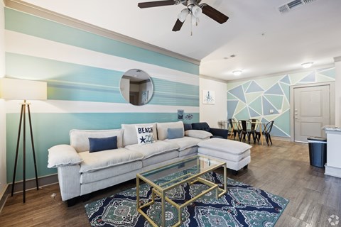 A living room with a white couch and a blue and white striped wall.