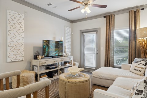 A living room with a television, a chair, a table, and a couch.