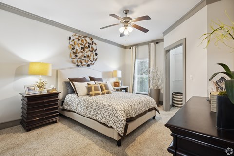 A bedroom with a bed, dresser, and ceiling fan.