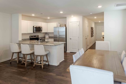 A kitchen with white cabinets and a wooden table.