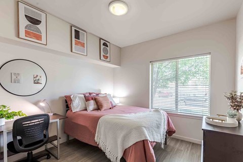 A bedroom with a bed, desk, and chair.