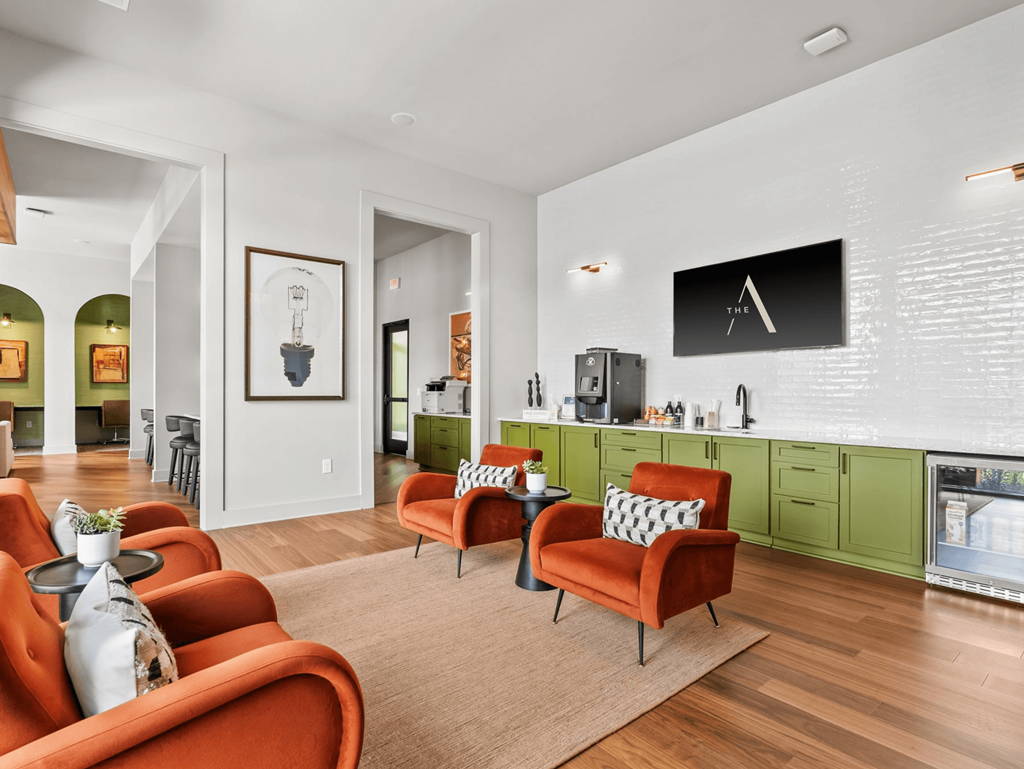 A living room with orange chairs and a television mounted on the wall.