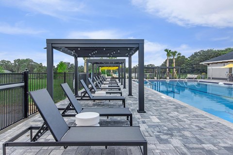 A poolside area with lounge chairs and a table.