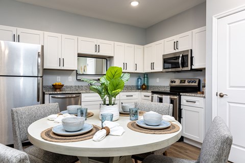 A modern kitchen with a dining table set for two.