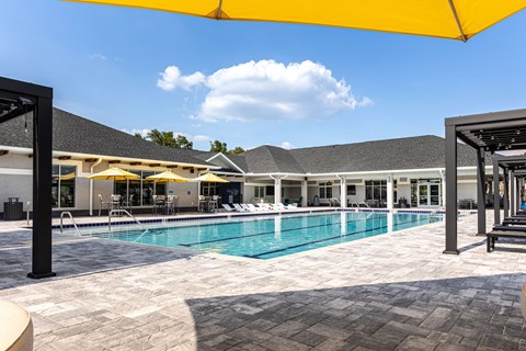 A large outdoor swimming pool with a yellow umbrella.