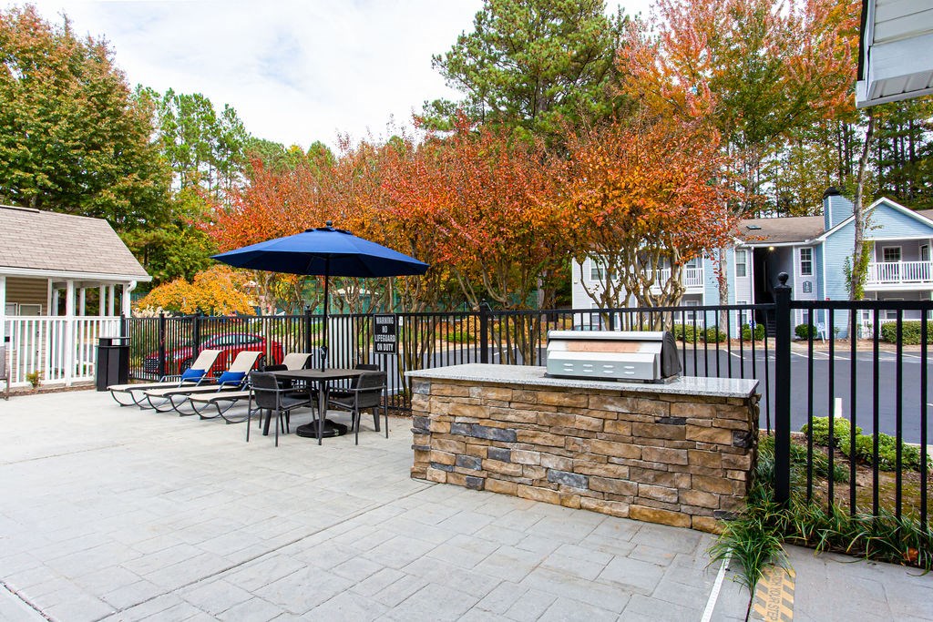 a patio with a grill and a table with chairs