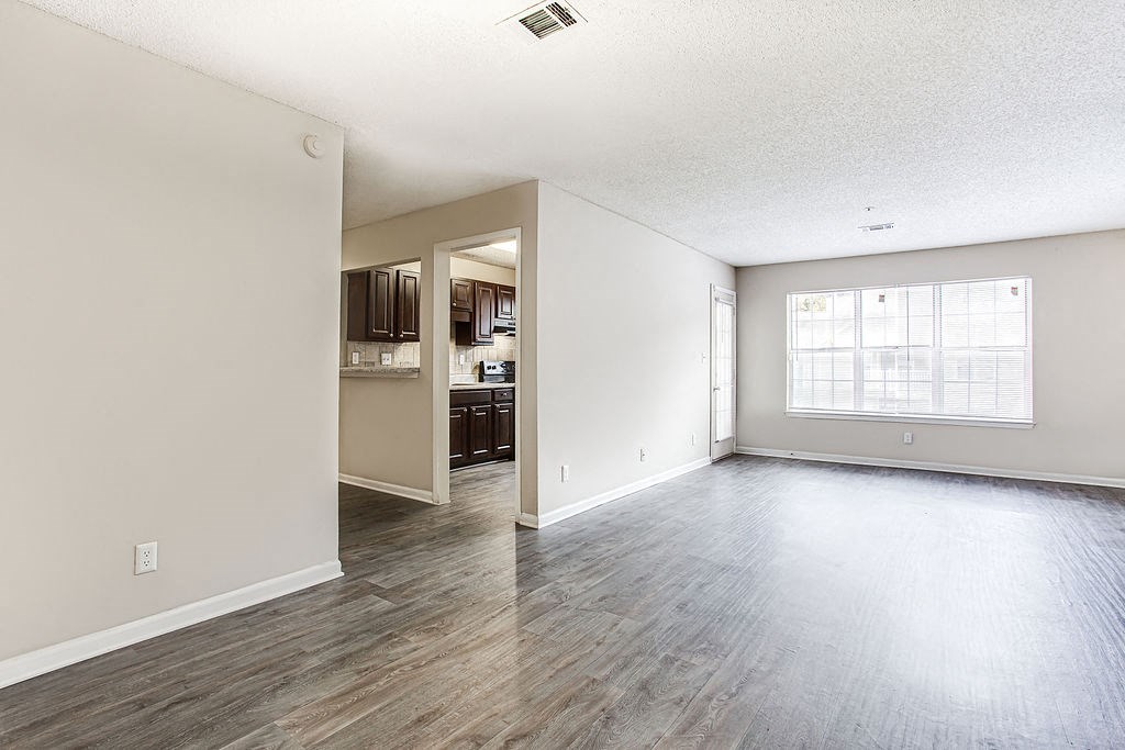 an empty living room and kitchen with wood floors