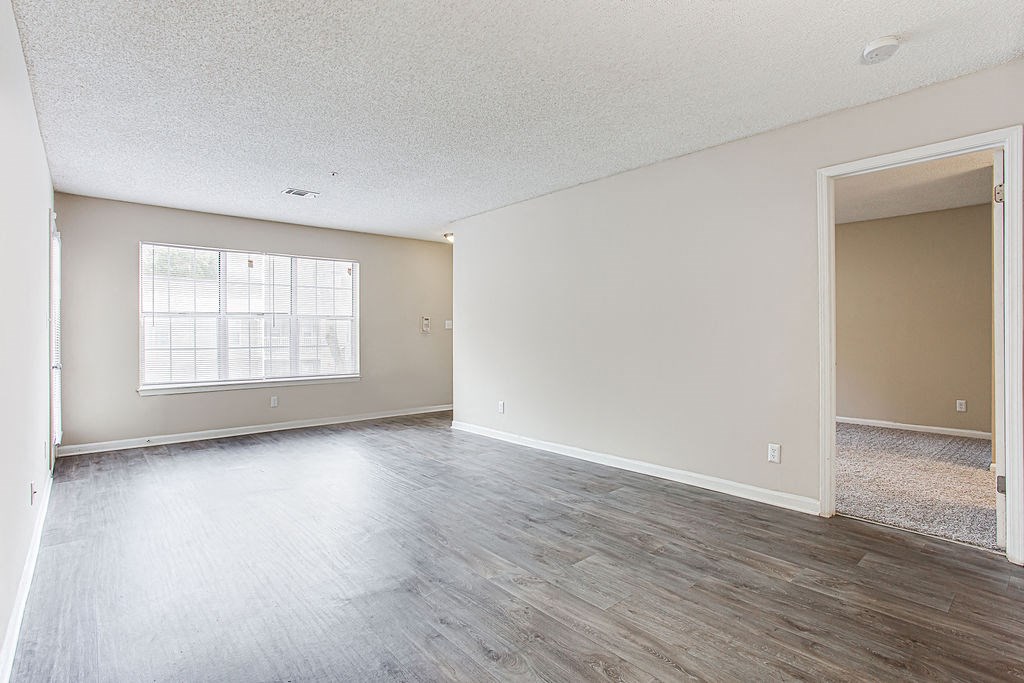 an empty living room with wood floors and a window