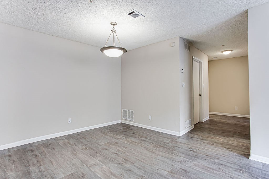the living room and dining room of an empty home with wood flooring