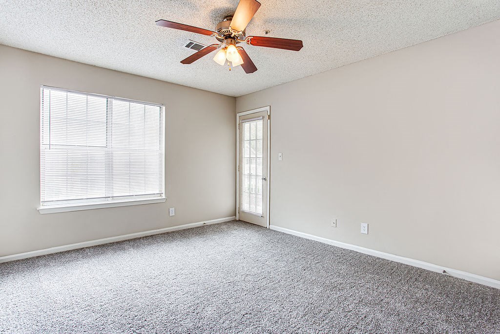 an empty living room with a ceiling fan and a window