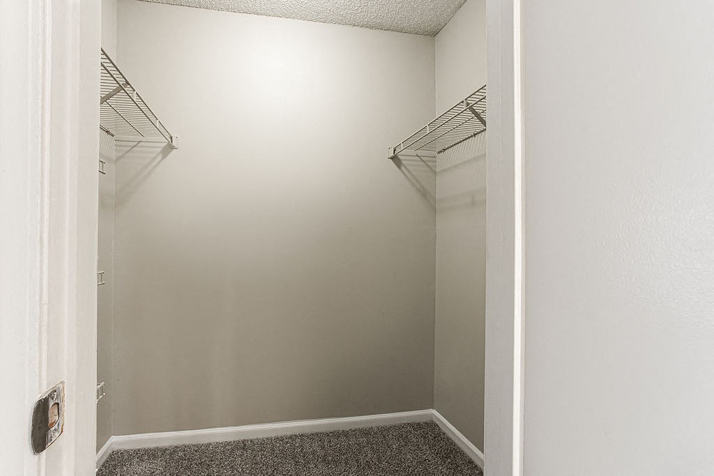 an empty walk in closet with two hanging racks