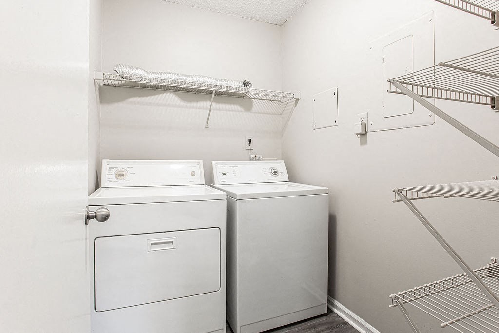 a washer and dryer in a white room with a shelf on the wall