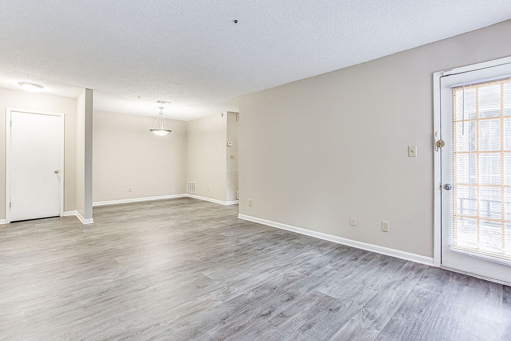 an empty living room with wood floors and a window