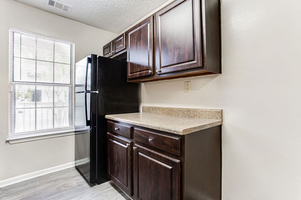 a kitchen with a refrigerator and cabinets and a window