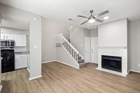 A living room with a fireplace and a staircase.