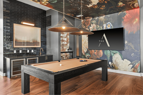 A pool table in a room with a black brick wall and a large painting.