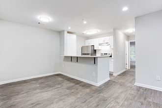 an empty living room with a kitchen in the corner