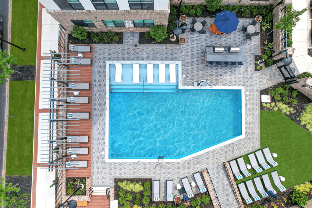 an aerial view of a swimming pool in a backyard with lounge chairs