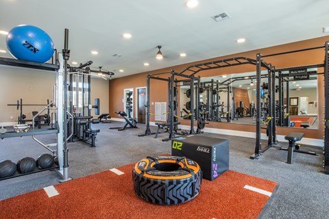 A gym with a variety of equipment including a blue exercise ball and a black and orange tire.