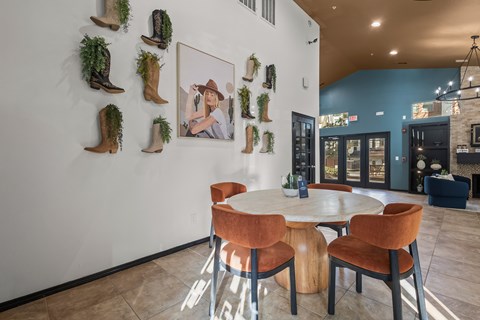 A room with a white table and chairs and a wall with a picture of a woman and cowboy boots.