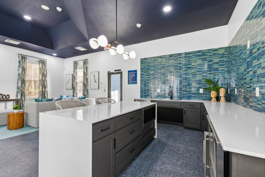 A modern kitchen with white countertops and a blue tiled backsplash.