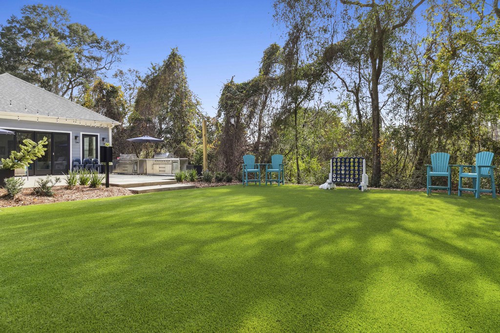 A backyard with a green lawn and blue chairs.