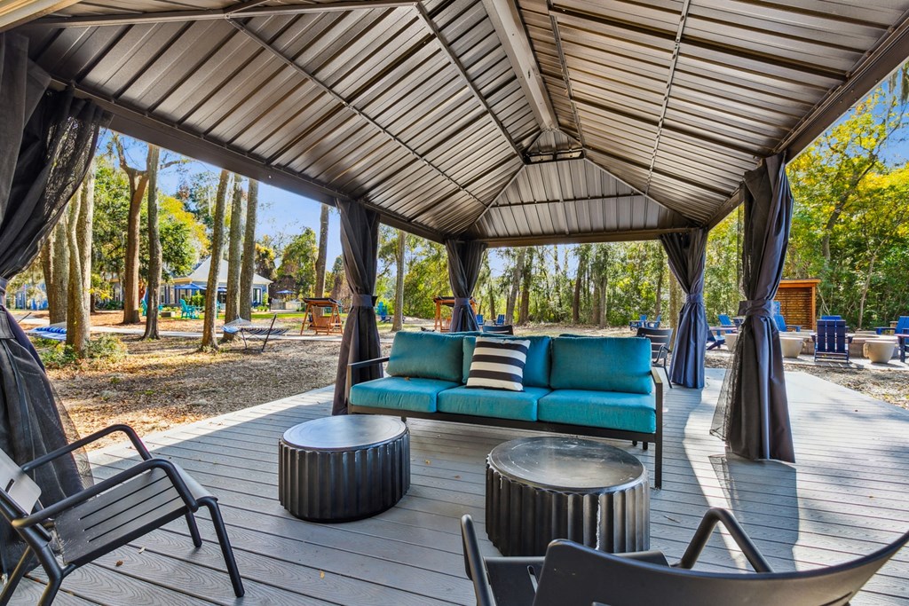 A wooden deck with a blue couch and a black chair.