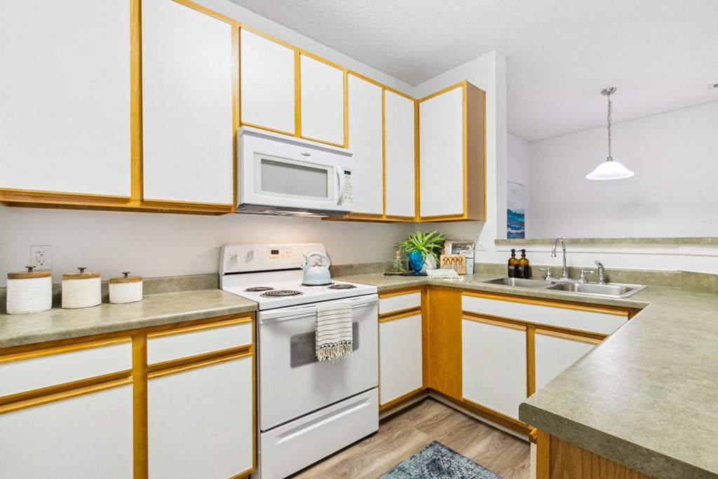 A kitchen with white cabinets and a white stove top oven.