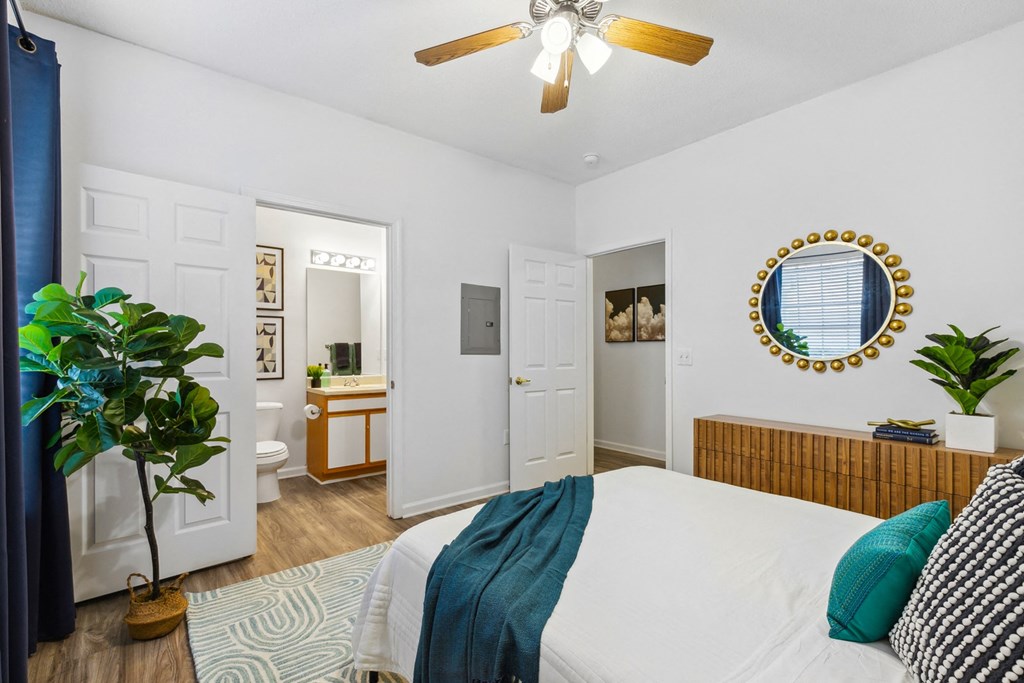 A bedroom with a bed, a ceiling fan, and a mirror on the wall.