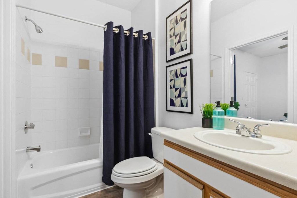 A white bathroom with a white toilet, a white sink, a white bathtub, and a white shower curtain.