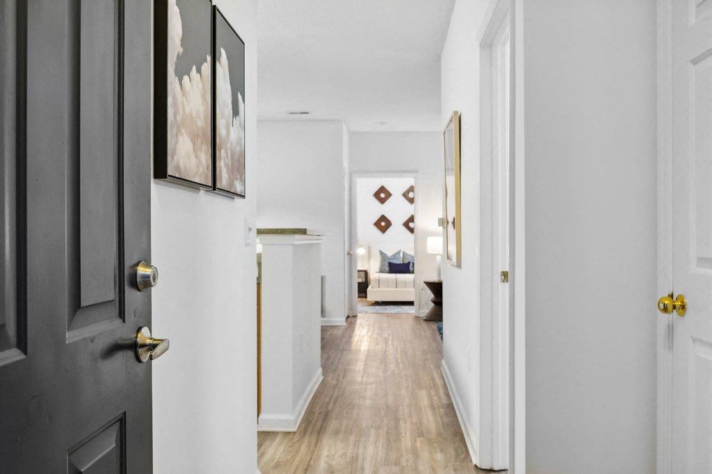 A hallway with a black door on the left and a white door on the right.