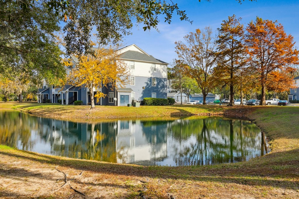 A serene pond in front of a house surrounded by trees.