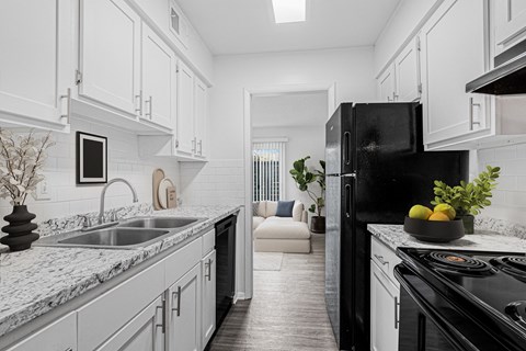 A modern kitchen with a black refrigerator and white cabinets.