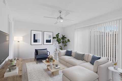 A living room with a white couch, a blue chair, and a ceiling fan.