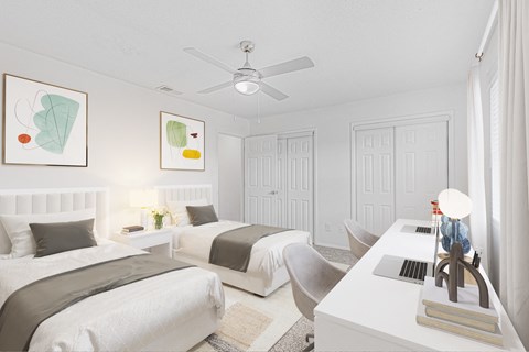 A bedroom with two beds, a desk, and a ceiling fan.