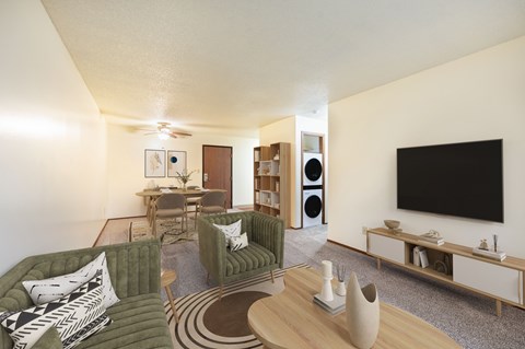 A living room with a green couch and a television on the wall.