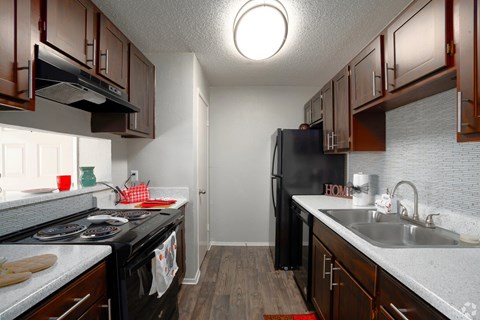 A kitchen with black appliances and wooden cabinets.