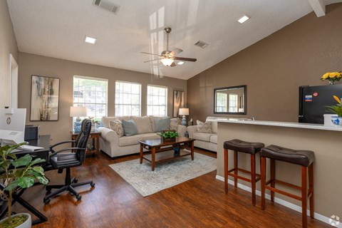 A living room with a bar stool and a ceiling fan.