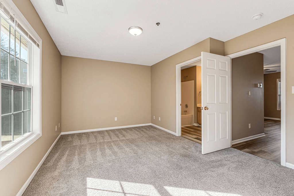 an empty living room with a white door and a door to a hallway