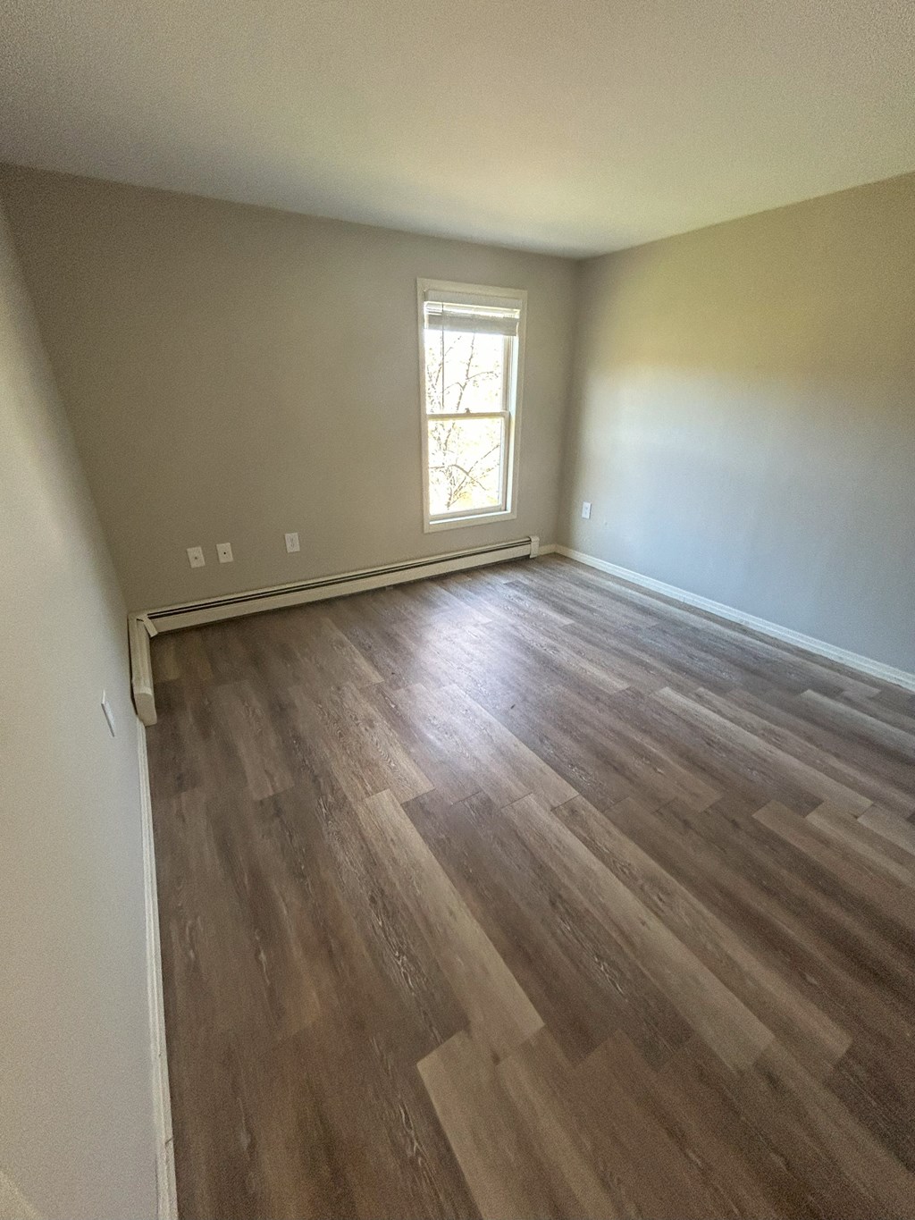 an empty living room with hardwood flooring and a window at Briarcliff at Quechee Apartments, Quechee, Vermont