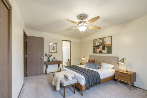 A bedroom with a bed, nightstand, and a ceiling fan.