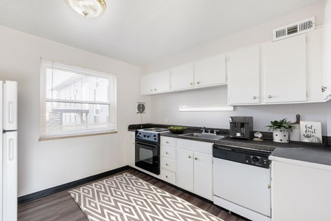 A kitchen with white cabinets and black countertops.
