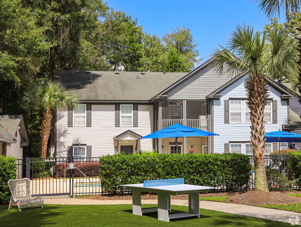 a white house with a picnic table and umbrellas