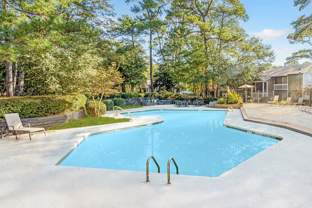 A large blue swimming pool surrounded by trees and a wooden deck. at Grove at St. Andrews, Columbia, SC