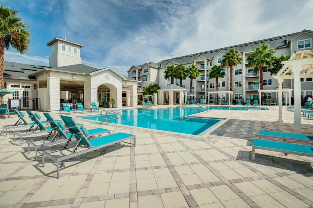 a swimming pool with chaise lounge chairs and a building in the background  at Century Avenues, Lakeland